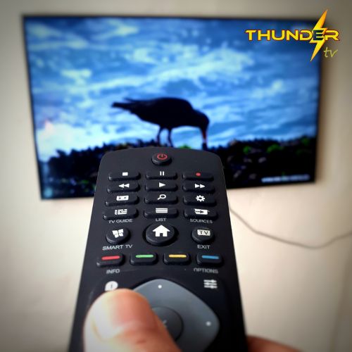 Control apuntando a una televisión con Logo de Thunder TV mostrando películas y canales en vivo